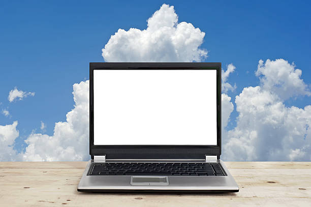istock laptop with blank screen on wooden table against sky background 492752548