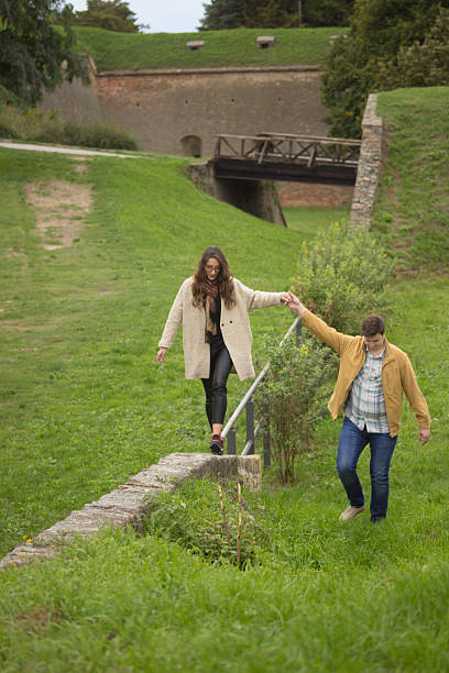 istock Boyfriend helping girlfriend while walking on narrow wall, in pa 492754292