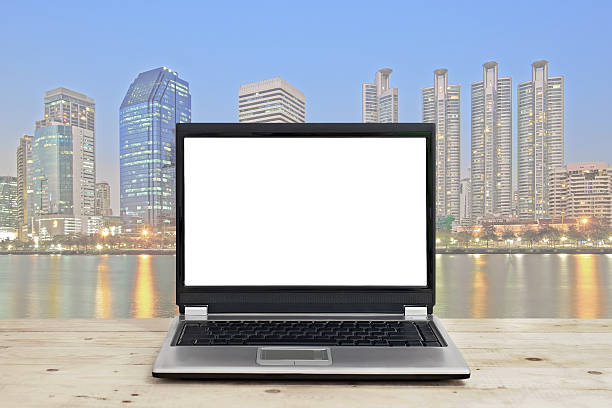istock laptop with blank screen on wooden table against cityscape background 492754910