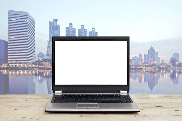 istock laptop with blank screen on wooden table against cityscape background 492755276