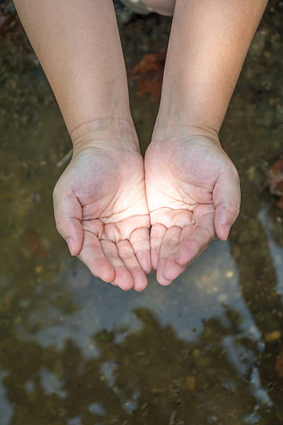 istock Asian woman hands with water in background 492755286
