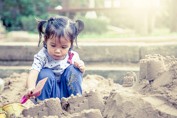 Child cute little girl playing with sand in playground Child playing with sand in playground,vintage filter sandbox photos stock pictures, royalty-free photos & images