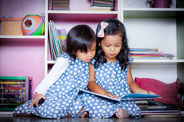 duas lindas meninas lendo livro juntos em livros - picture book library preschool bookshelf - fotografias e filmes do acervo