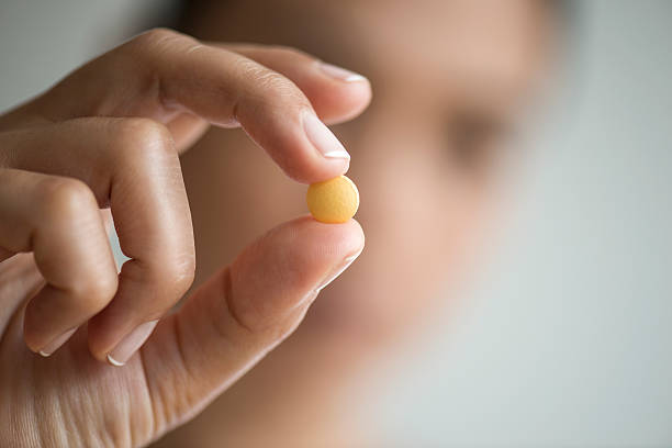 Woman Holding And Showing Yellow Pill