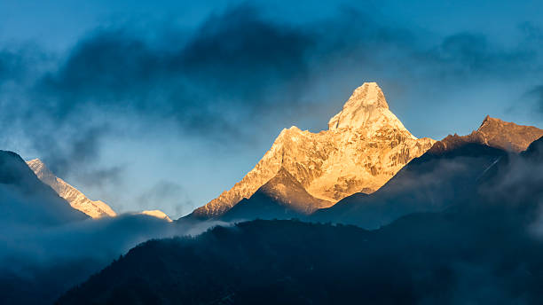 Sunset over Mount Ama Dablam, Himalayas, Nepal Ama Dablam is a mountain in the Himalaya range of eastern Nepal. The main peak is 6,812  metres (22,349 ft), the lower western peak is 5,563 metres (18,251 ft). Ama Dablam means  "Mother's neclace"; the long ridges on each side like the arms of a mother (ama) protecting  her child, and the hanging glacier thought of as the dablam, the traditional double-pendant  containing pictures of the gods, worn by Sherpa women. For several days, Ama Dablam dominates  the eastern sky for anyone trekking to Mount Everest basecamp.http://bem.2be.pl/IS/nepal_380.jpg solu khumbu stock pictures, royalty-free photos & images