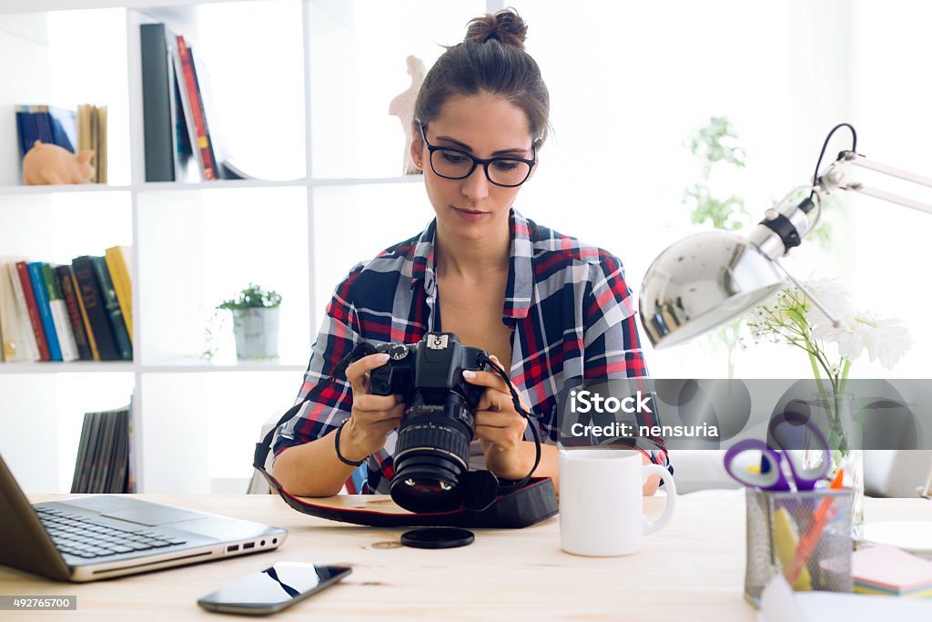 Young woman photographer checking previews on camera in the stud Portrait of young woman photographer checking previews on camera in the studio. Photographer Stock Photo