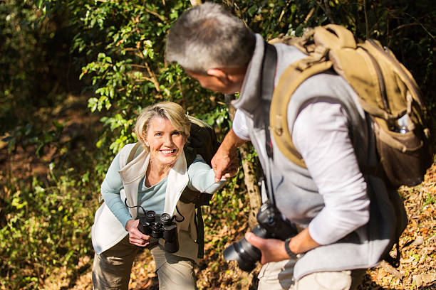 istock man helping his wife climbing mountain 492766464