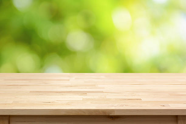 istock Wood table top on bokeh abstract green background 492774660