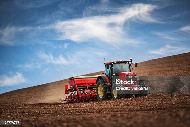 Farmer With Tractor Seeding Crops At Field Stock Photo - Download Image Now - Tractor, Agricultural Machinery, Agriculture