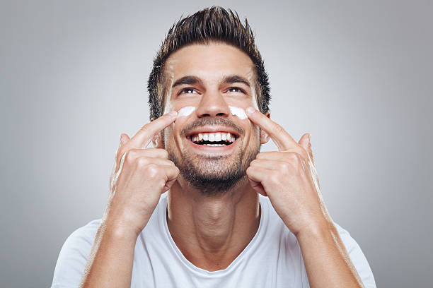 Young man with moisturizer on the face stock photo