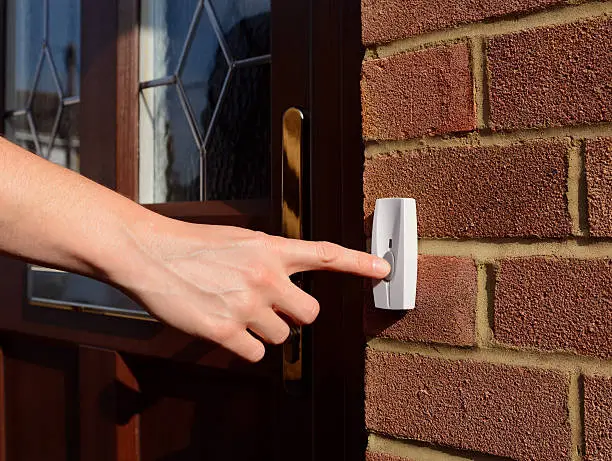 Photo of Woman extends her hand to ring doorbell