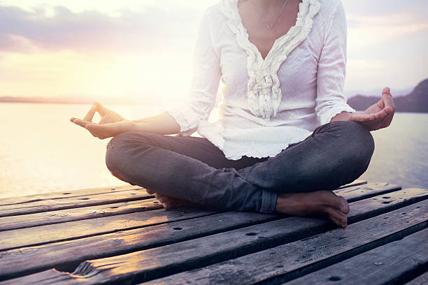 istock beautiful woman meditating on a boardwalk at sunset 492778160