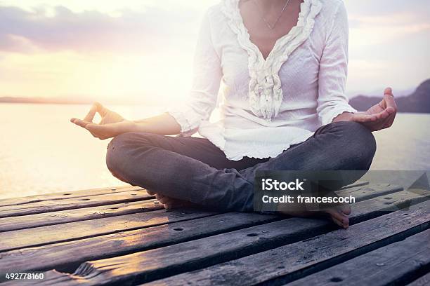 Beautiful Woman Meditating On A Boardwalk At Sunset Stock Photo - Download Image Now