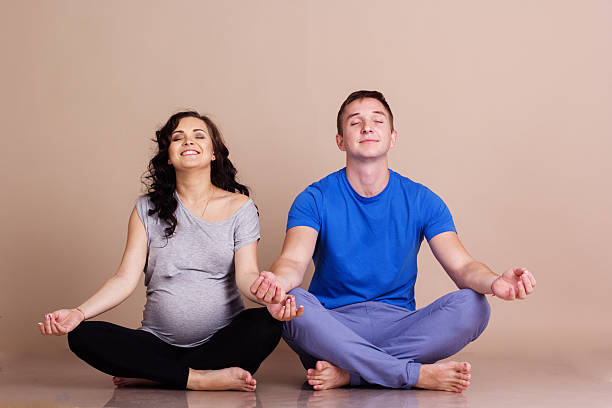 Pregnant girl and man doing yoga stock photo