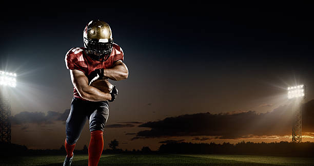 American football in action A male american football player makes a dramatic play. The panoramic view of stadium is behind him. The sky is dark and cloudy behind him.  The player is wearing generic unbranded american football uniform. The stadium is 3D rendered. football player stock pictures, royalty-free photos & images