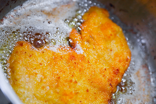 Deep fried meat coated in bread crumbs in hot oil.