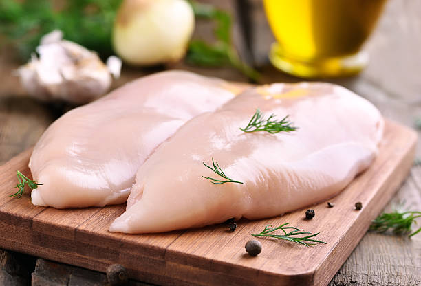 las pechugas de pollo en tabla de cortar - pechuga de pollo fotografías e imágenes de stock