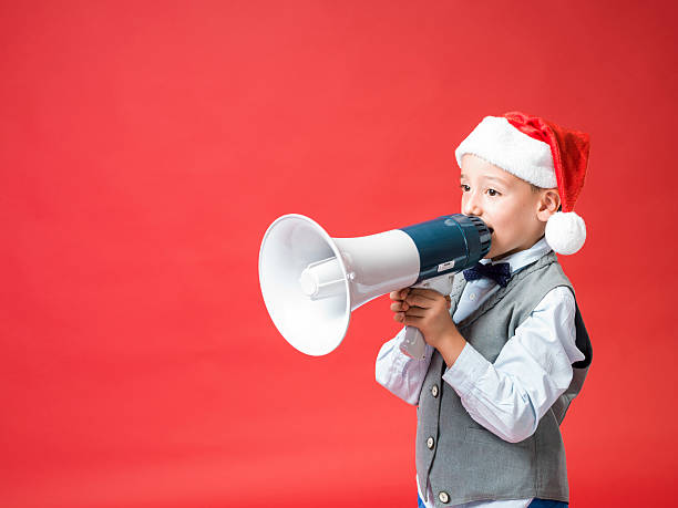 istock Little boy with santa hat shouting on old fashioned megaphone 492789266