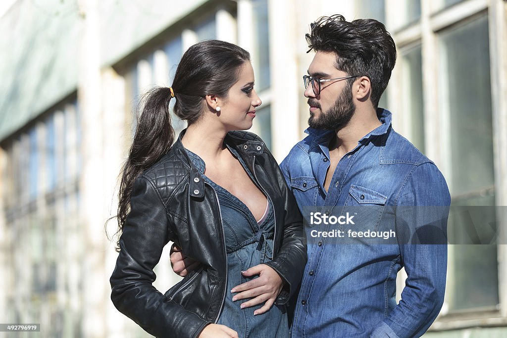 young man and woman look at each other young casual couple looking at each other and smiling while he is embracing her Adult Stock Photo