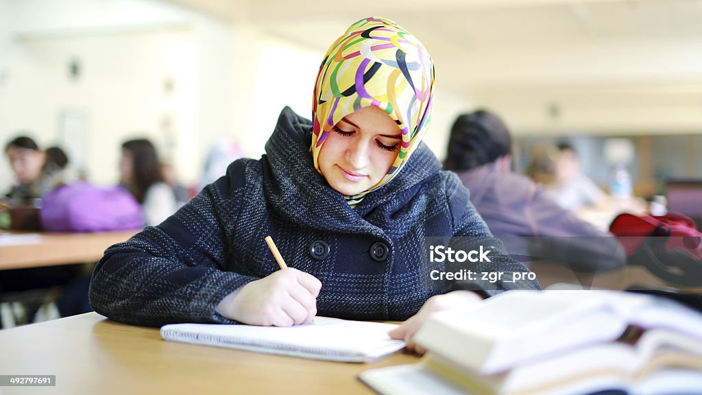 Ragazza musulmana studiando in biblioteca - Foto stock royalty-free di Donne