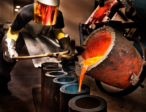 Worker pouring liquid metal into crucible.