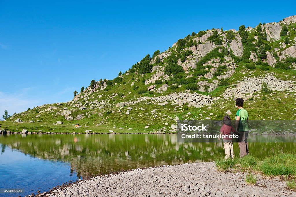 Mother and Daughter on Lake Shore A caucasian mother and her daughter standing on the shore of an alpine lake. Paneveggio. Trento Province. Trentino-Alto Adige. Italy. Child Stock Photo