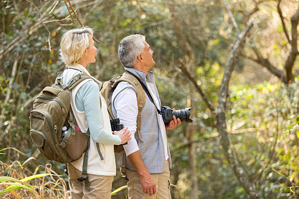 istock middle aged couple bird watching in forest 492806852