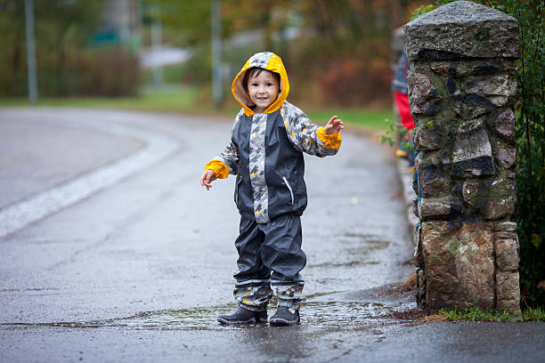 istock Cute boy in park, playing in rain, jumping in puddles 492809258