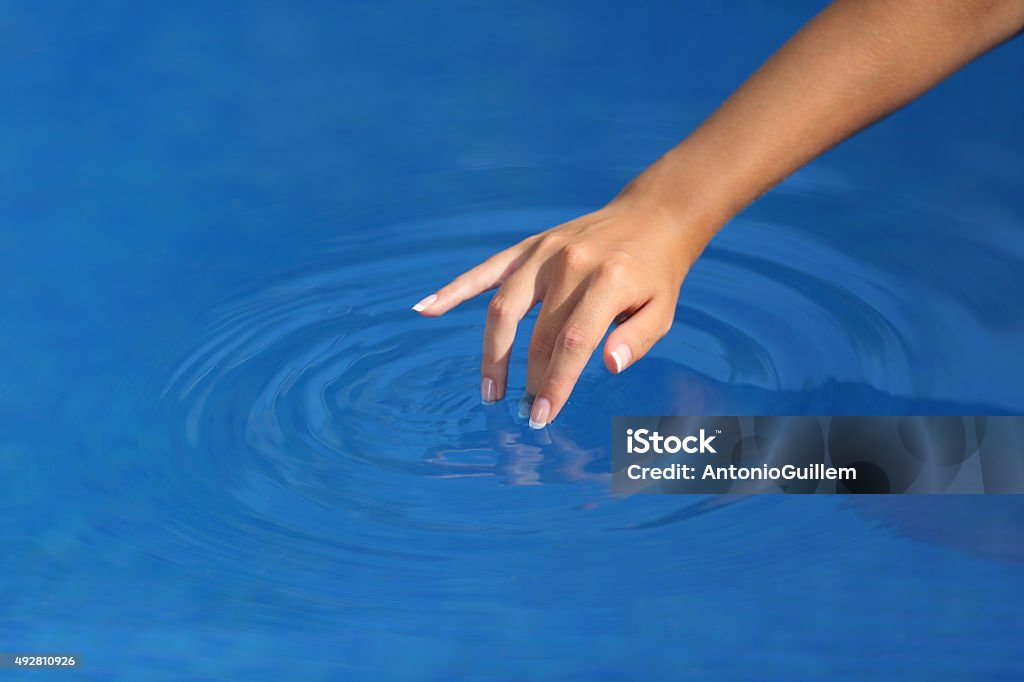 Woman hand with perfect manicure playing with water in pool Close up of a woman hand with perfect manicure playing with clean water in a pool with a blue background Swimming Pool Stock Photo