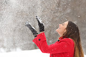 Woman in red throwing snow in the air in winter