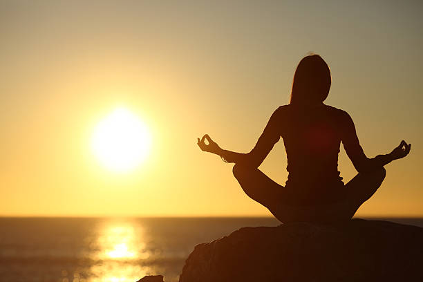 istock Woman meditating and practicing yoga watching the sun 492811156