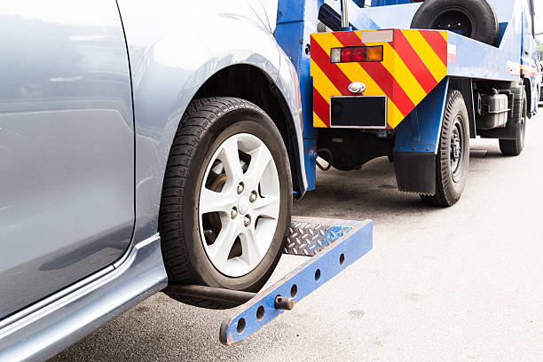 Tow truck towing a broken down car on the street Tow truck towing a broken down car on the street. roadside stock pictures, royalty-free photos & images