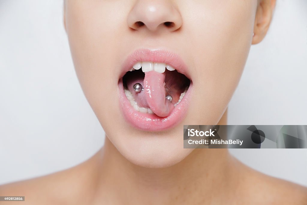 Hermosa mujer sacando su lengua y que muestra joven perforación - Foto de stock de Agujereado libre de derechos