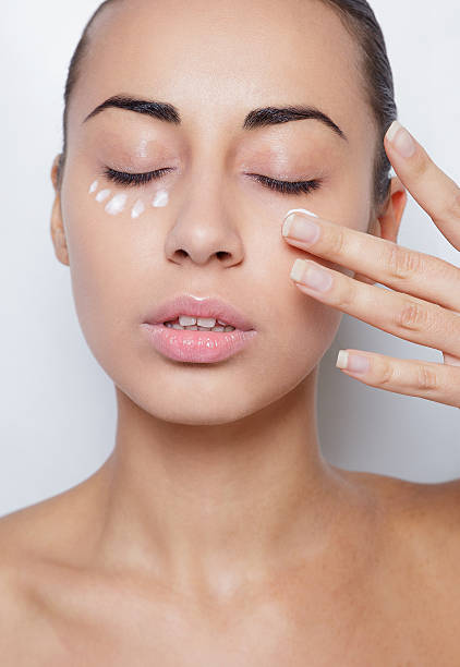 istock beautiful model applying cosmetic cream treatment on her face white 492814428