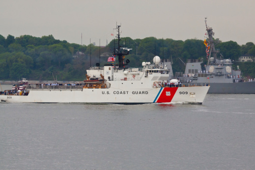 New York, NY, USA - May 21, 2014: Coast Guard and USS Cole destroyer entering New York Harbor, for a Fleet Week. Fleet Week has held since 1984 to honor the U.S. Navy and Marine Corps. Image taken from Shore Promenade in Brooklyn. Sailors are lined up on the deck of Coast Guard ship and USS Cole.