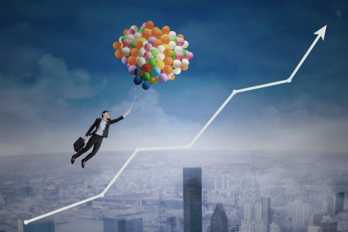 Young businesswoman flying with balloons over upward arrow symbolizing growing business