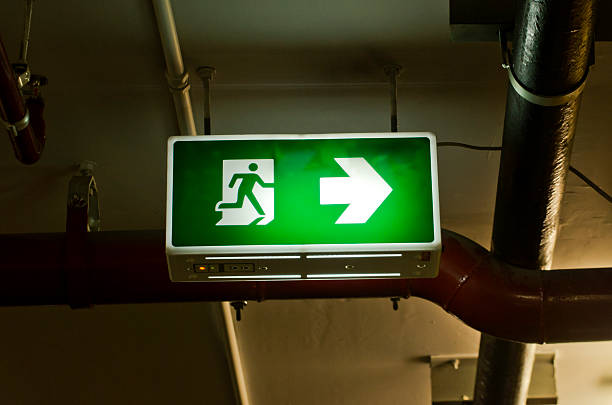 letrero de salida colgante iluminado verde desde el techo. - people metal sign way out sign fotografías e imágenes de stock
