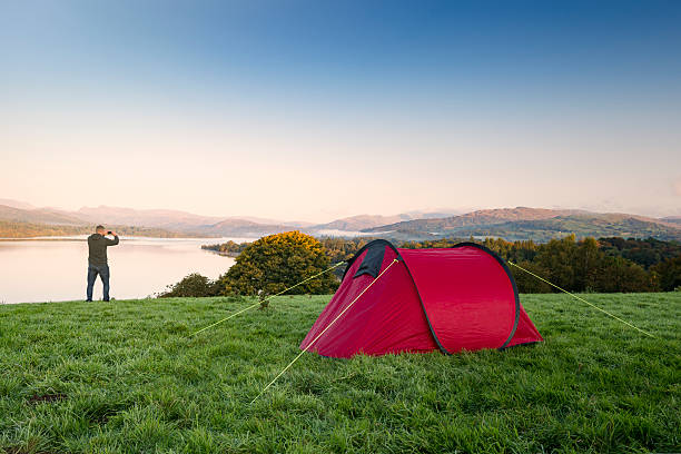 Man stood next to a red tent on a hill