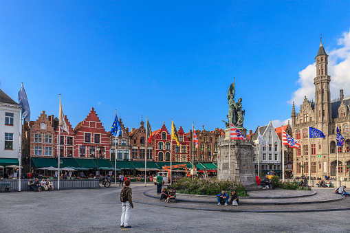Bruges, Belgium - September 10, 2014: Tourists visiting the Markt -Market Square- in old town of Bruges, overlooked by notable buildings, such as the Provincial Court and the 13th-century Belfry, one of the landmarks of the city. The square covers an area of about 1 hectare and was completely renovated in 1996, becoming a traffic-free area.