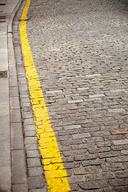 istock Curb and yellow line on cobblestone street. 492843174