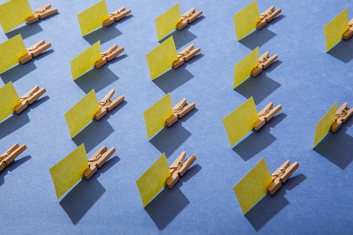 Miniature post it notes and clothespins arranged on a colored background. 