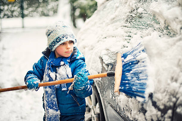 маленький мальчик что чистый семейный автомобиль после зимних attack - snow cleaning стоковые фото и изображения