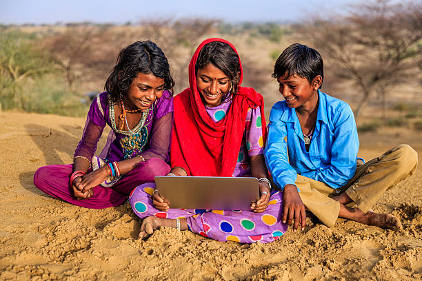 Happy Indian children using laptop, desert village, India