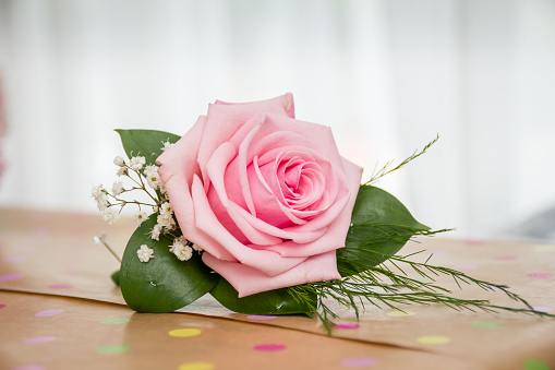 Single pink rose for groom's buttonhole, resting on a brown box
