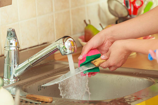 Household. Closeup woman doing the washing up in kitchen