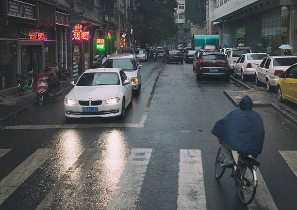 Xi'an, China - May 23, 2014. People driving cars and riding bicycles in the rain on the streets in downtown Xi'an, China.