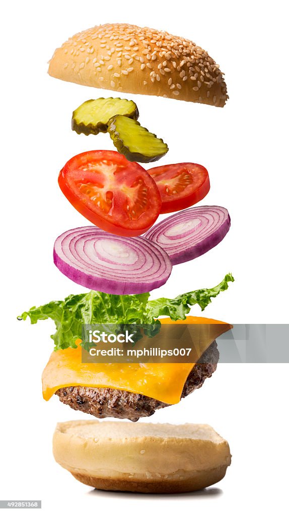 Cheeseburger Exploded View A cheeseburger being dropped into place.  The cheeseburger exploded view contains lettuce, red onion, tomato, and pickle with the bun top falling into place.  The photograph is on pure white for easy compositing.  Please see my portfolio for other food images.  Hamburger Stock Photo