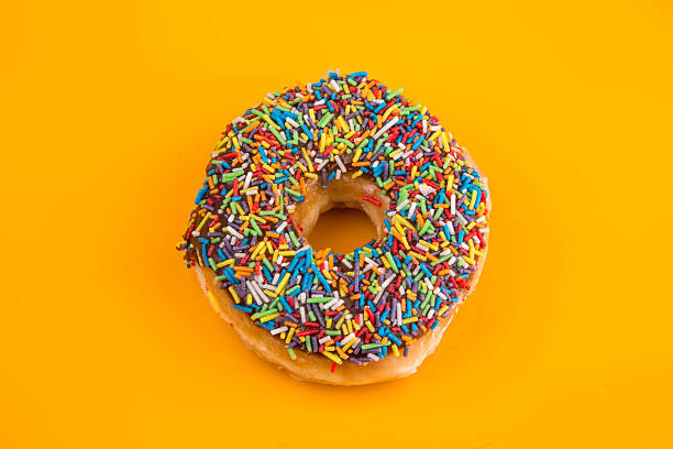 istock Donut with sprinkles on yellow background 492852806