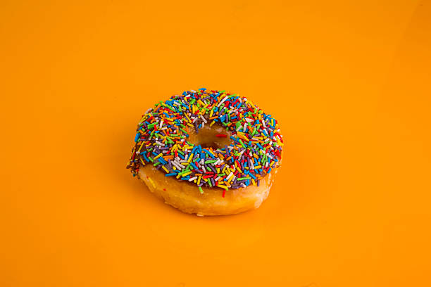 istock Donut with sprinkles on yellow background 492852876