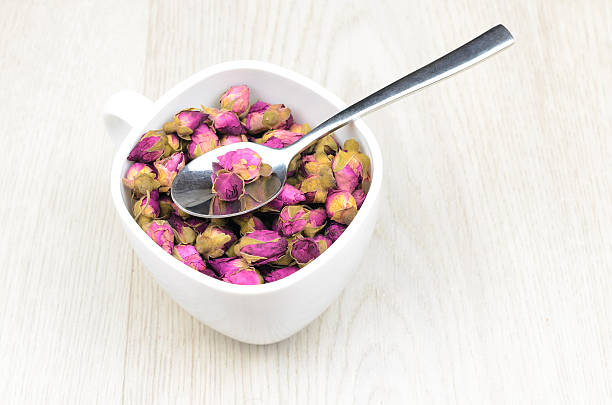 istock tea roses in a white cup on wooden table 492854598